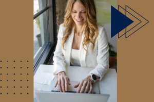 Professional real estate agent in a white blazer working on a laptop by a bright window, helping clients get mortgage pre-approved in FishHawk Ranch.